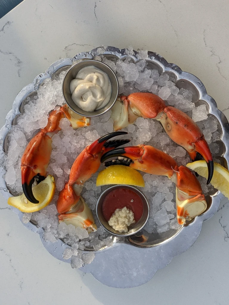 Fresh stone crab claws on ice with lemon and two sauces.