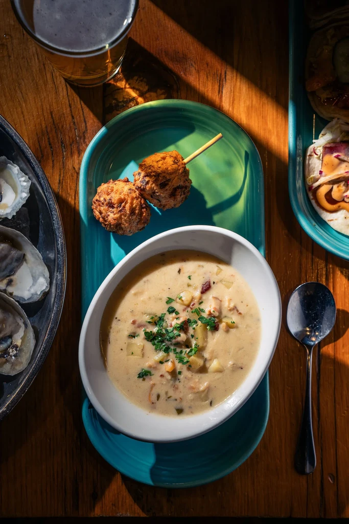 Overhead view of a table with beer, oysters, chowder, and tacos.