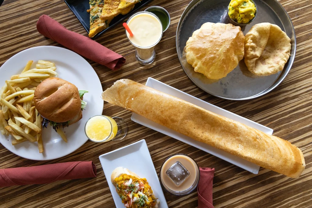 Table spread with diverse Indian and international dishes and drinks.