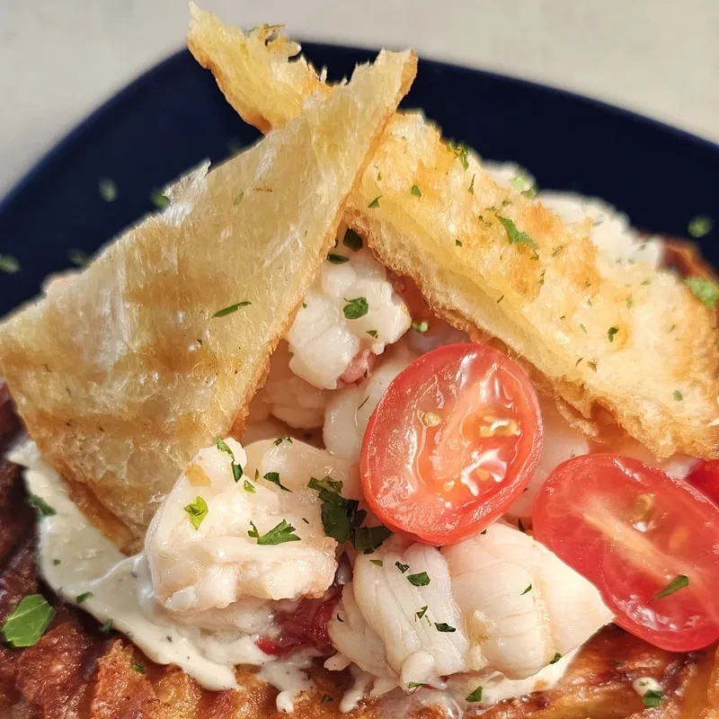 Gourmet shrimp dish with crispy pastry, creamy sauce, and herbs.