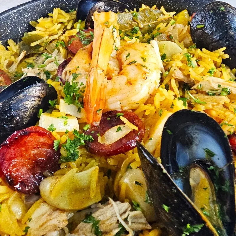 Close-up of colorful seafood paella with shrimp, mussels, chorizo, and rice.