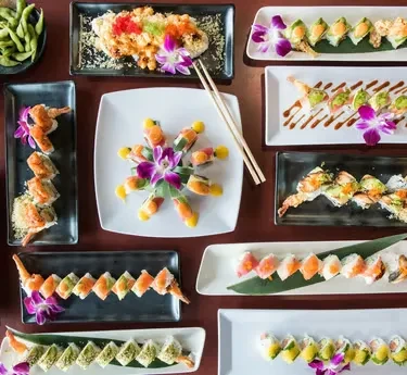 Top-down view of a vibrant, artfully arranged sushi and appetizer spread.