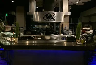 Sushi restaurant counter with refrigerated display and octopus exhaust hood.