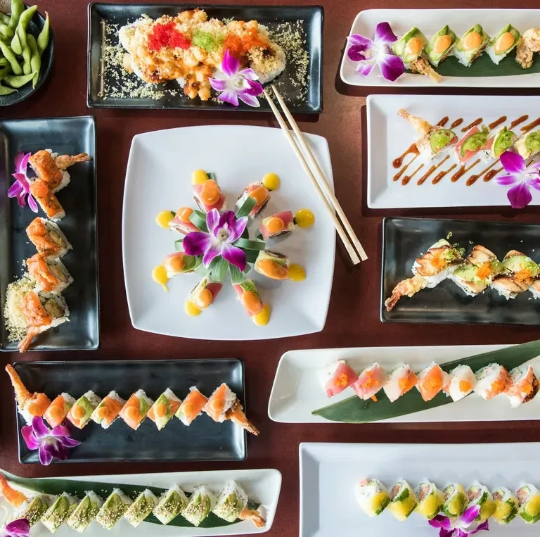 Overhead shot of diverse, colorful sushi and maki rolls, artfully presented.