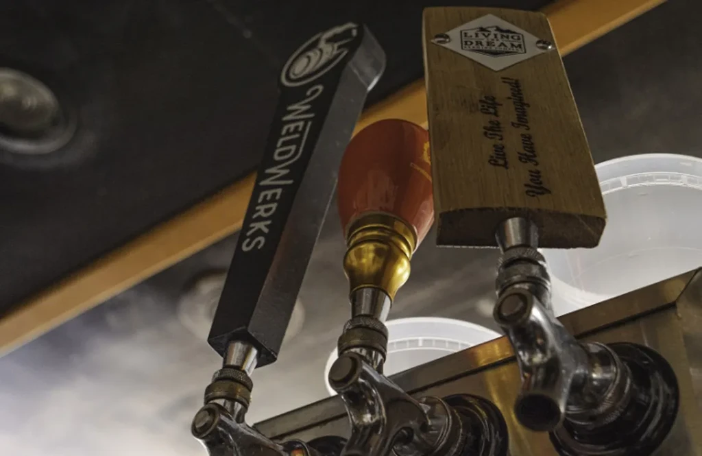 Close-up of three distinct beer tap handles on a stainless system.