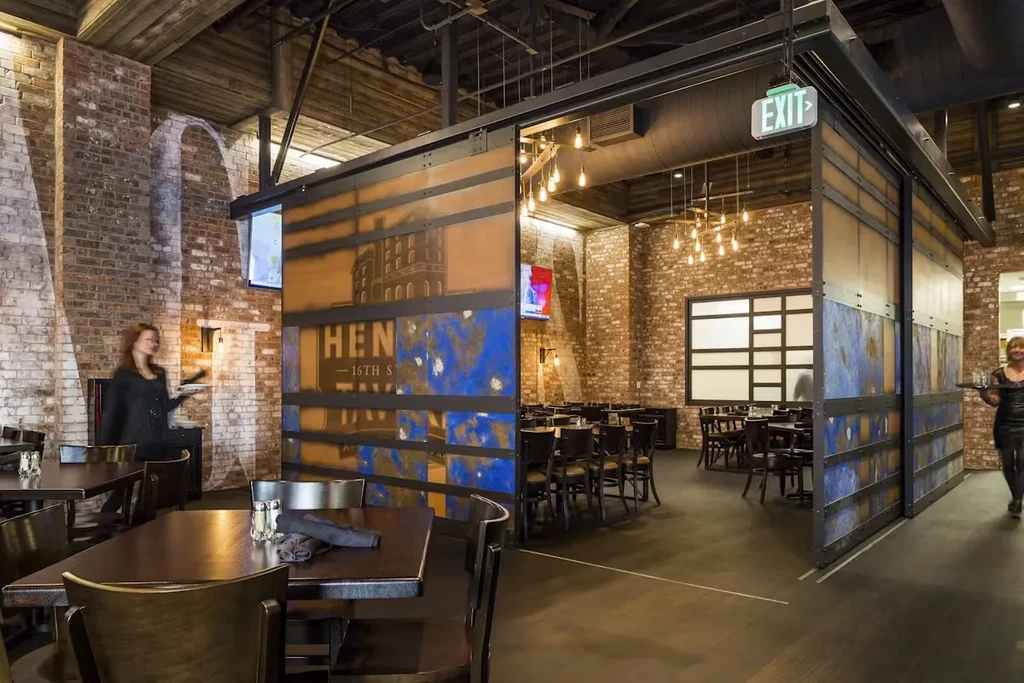 Industrial-chic restaurant with exposed brick, wooden ceiling, and metallic partition.