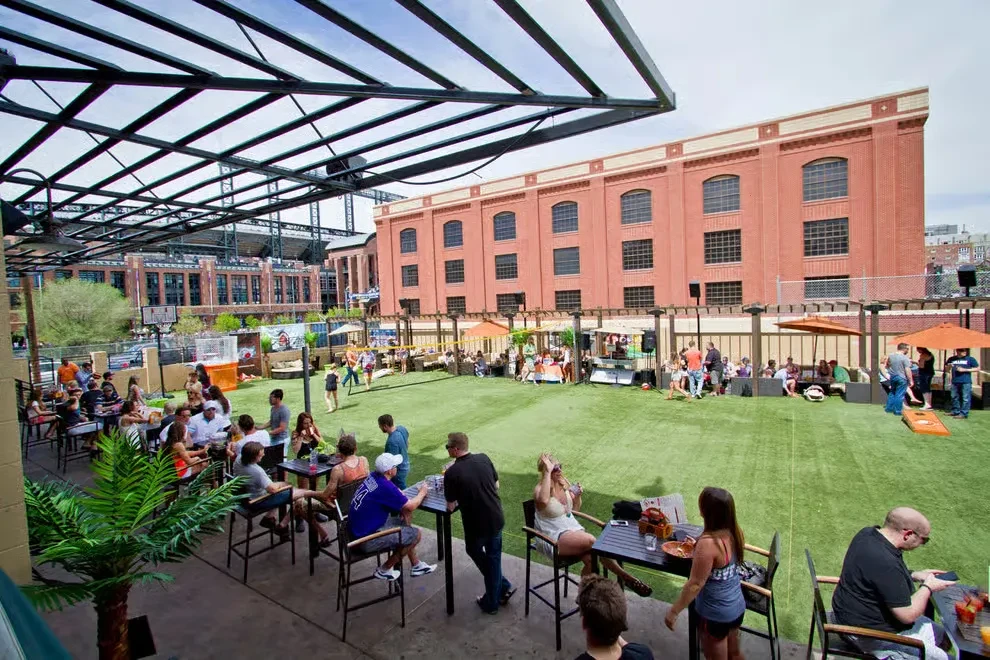 Outdoor beer garden with turf lawn, people playing games, socializing.