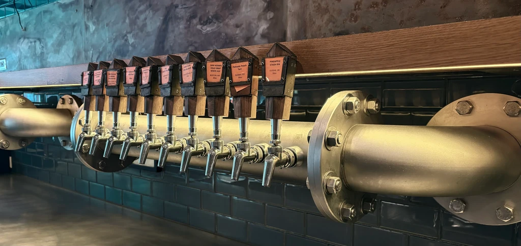Modern industrial beer tap system with ten chrome taps and beer labels.