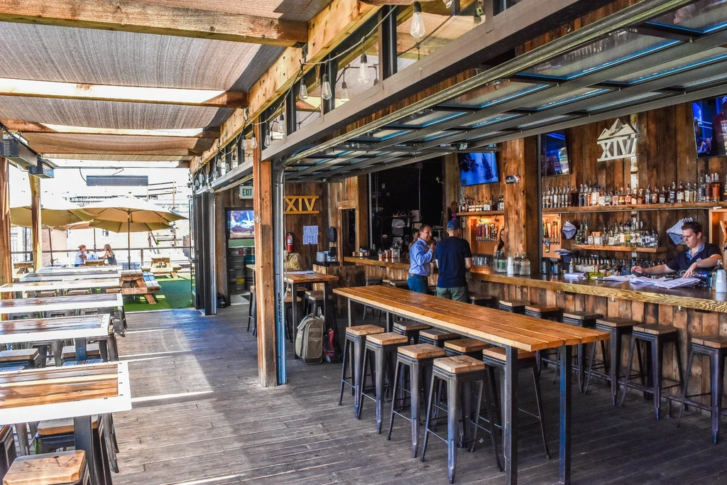 Modern rustic bar and patio connected by a wide opening.
