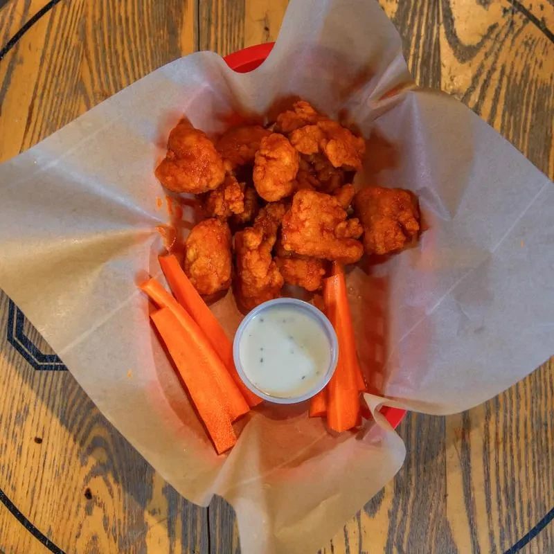 Basket of Buffalo chicken bites with carrots and ranch dip.