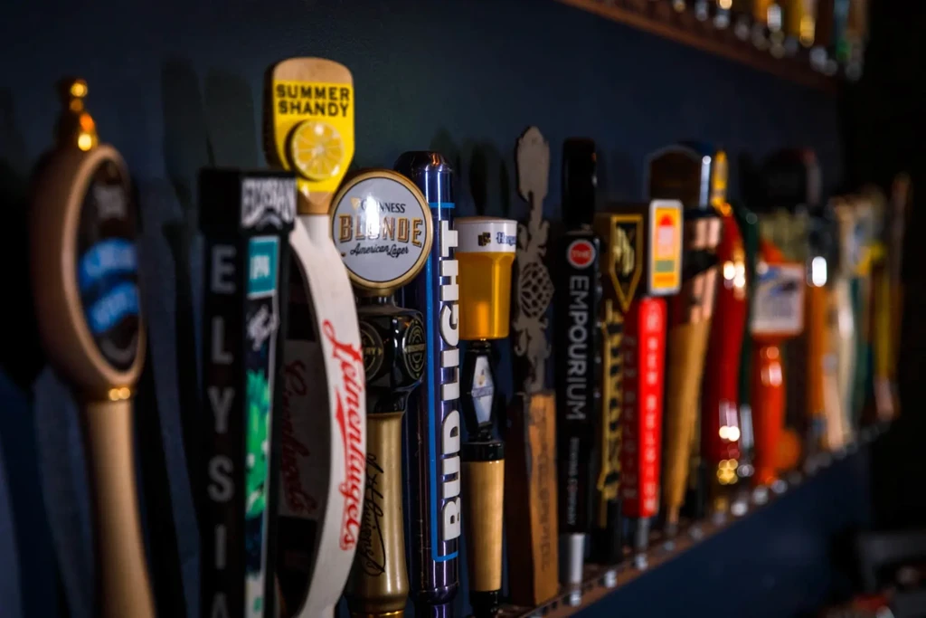 Variety of branded beer tap handles in a dimly lit bar.