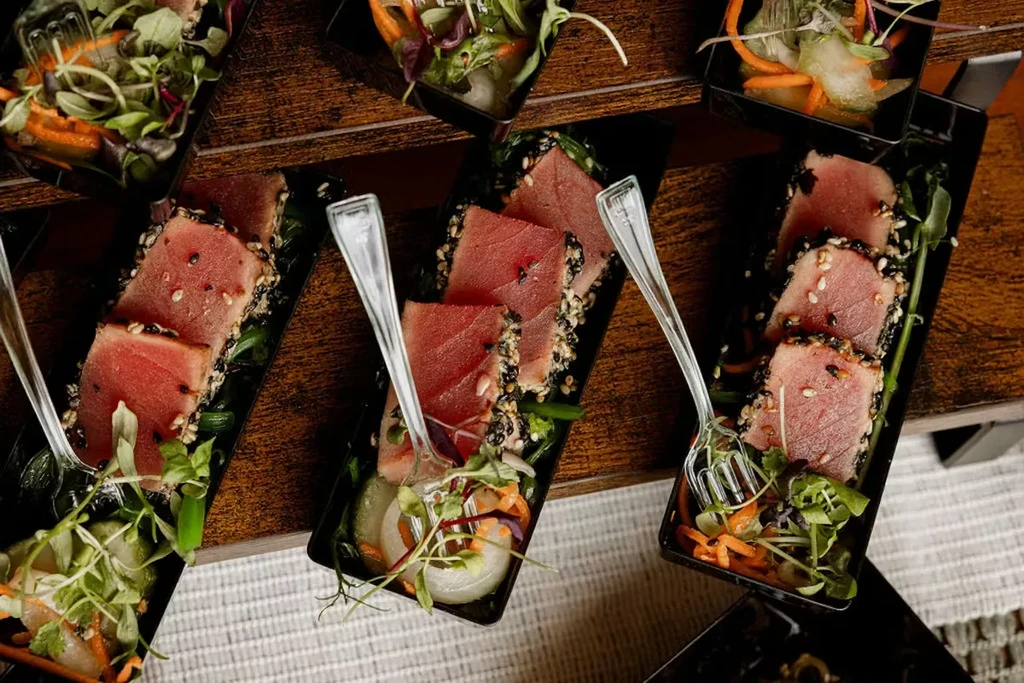 Seared sesame-crusted tuna appetizers on a tiered wooden stand.