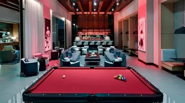 Red-lit modern lounge with a pool table, seating, and bar.