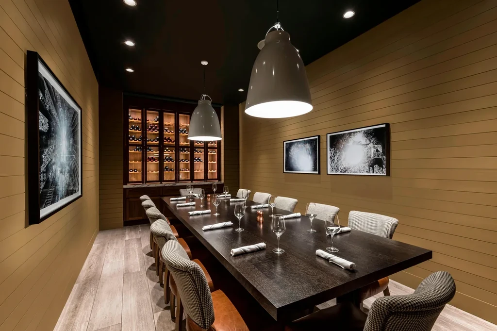Elegant private dining room with long set wooden table and wine cabinet.