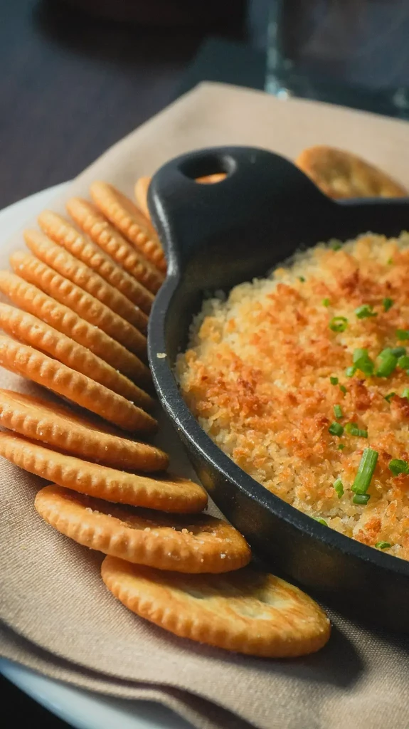 Golden-brown hot dip in a skillet with crackers and chives.