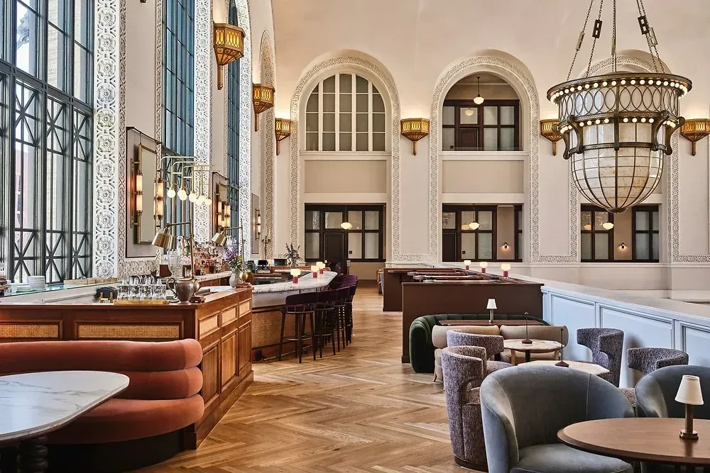 Elegant, empty restaurant interior with a curved bar, arched windows, and ornate lighting.