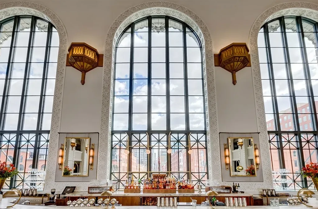 Bright, elegant bar with arched windows and a well-stocked marble counter.