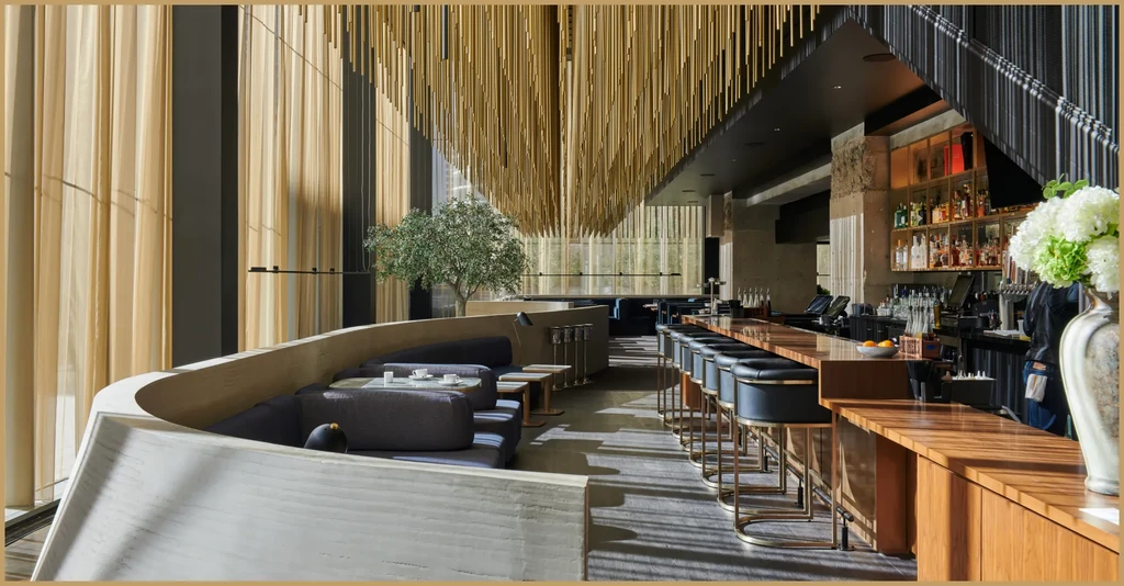 Upscale modern bar and restaurant with banquettes, olive tree, and golden ceiling.