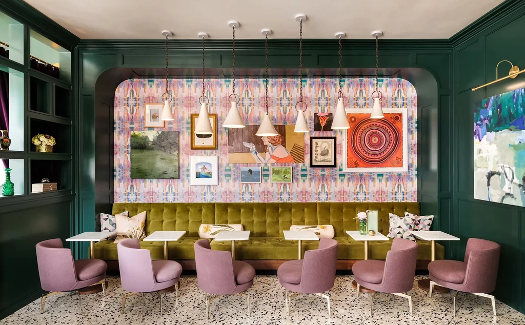 Eclectic restaurant interior with green velvet banquette and abstract wall.