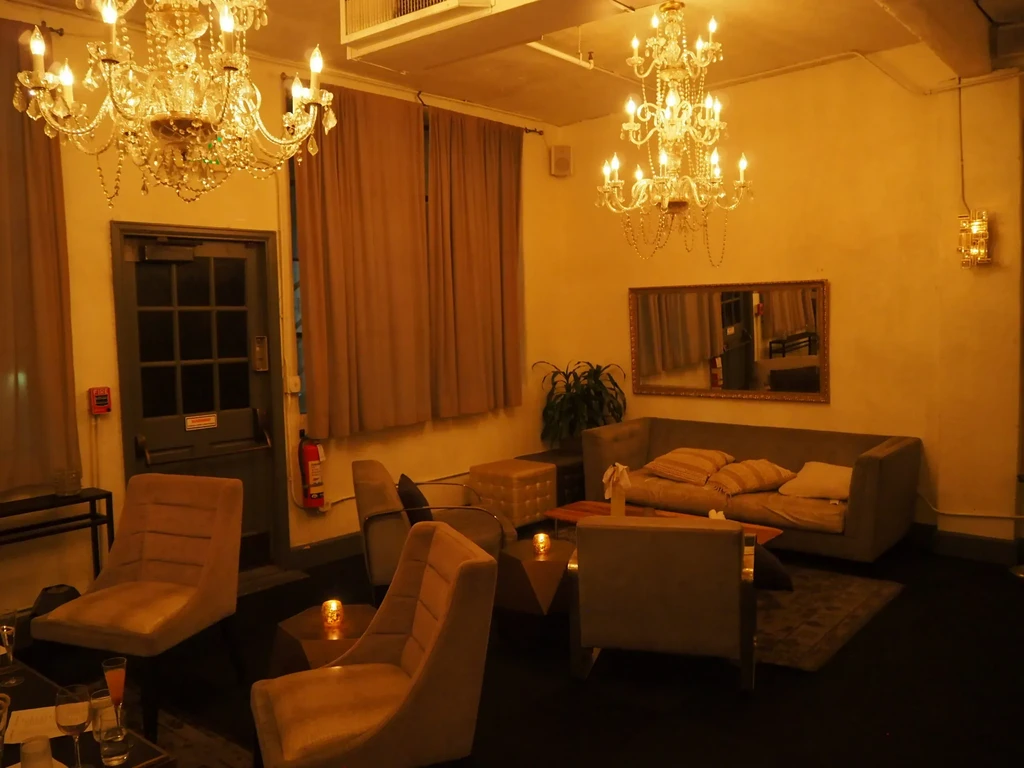 Dimly lit lounge interior with crystal chandeliers and upholstered seating.