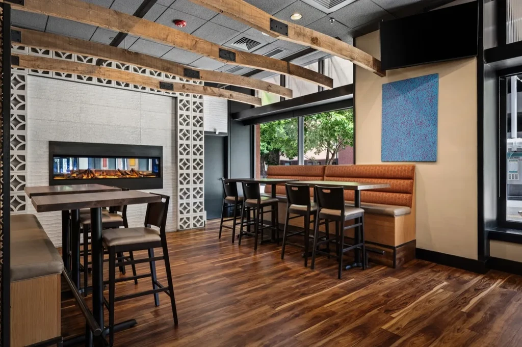 Modern rustic restaurant interior with fireplace, booths, and bar seating.