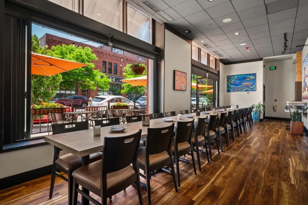 Long restaurant dining room with art opens to a street patio.