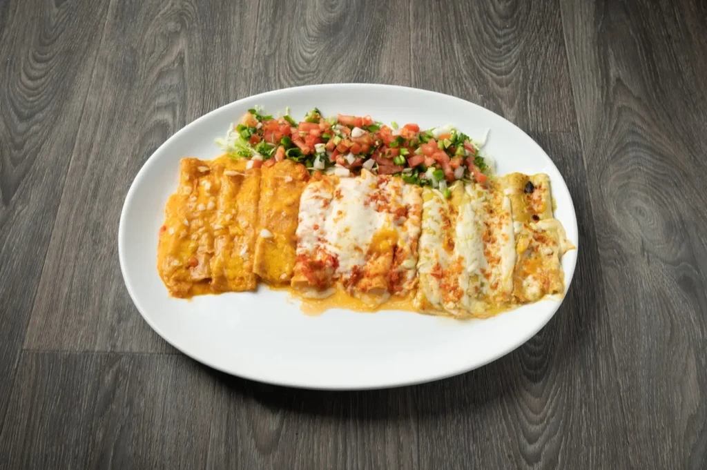 Three enchilada sections with orange, red, green sauces, cheese, and pico.
