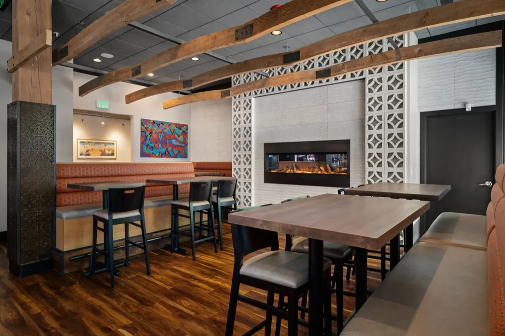 Modern restaurant with rust orange booths, exposed beams, and contemporary fireplace.
