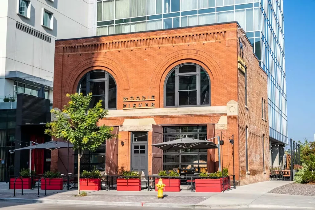 Two-story brick Woodie Fisher restaurant with arched windows and outdoor patio.
