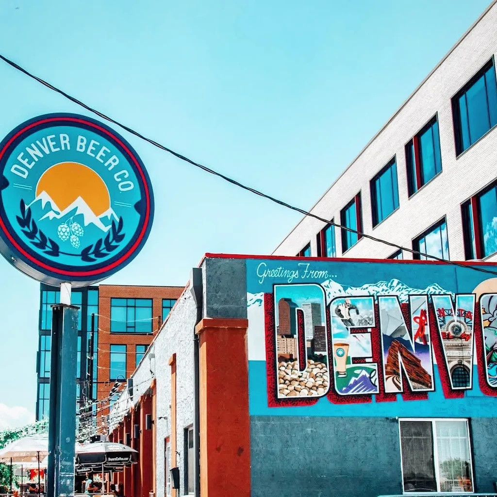 Denver Beer Co building, 'Greetings From DENVER' mural, and busy outdoor patio.