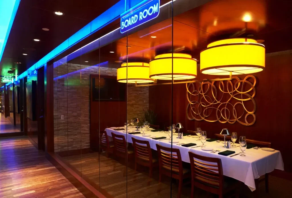 Board Room with set table, yellow lights, seen from blue hallway.