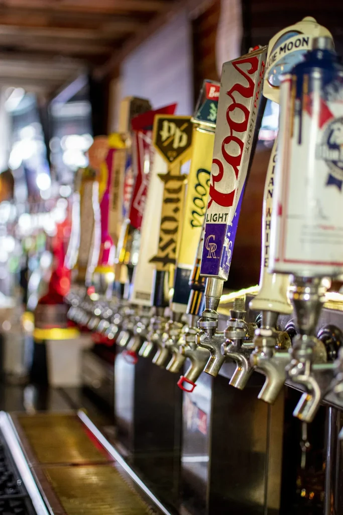Gleaming beer tap handles at a bar, including Coors Light and Blue Moon.