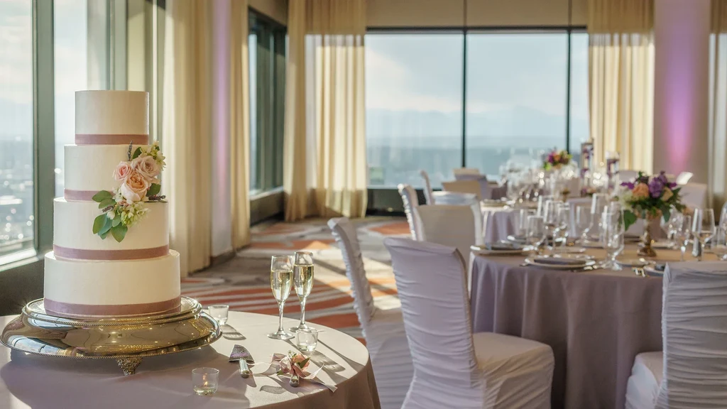 An elegant event room with a four-tiered wedding cake and city skyline.
