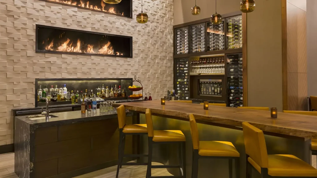 Upscale modern bar with two fireplaces, wine storage, and yellow stools.