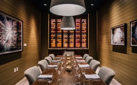 Elegant private dining room with set wooden table and prominent wine display.
