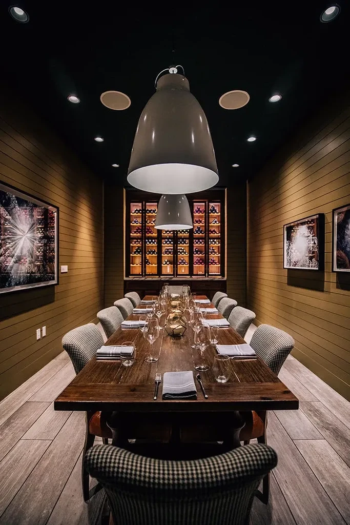 Long table in elegant private dining room with wine display.