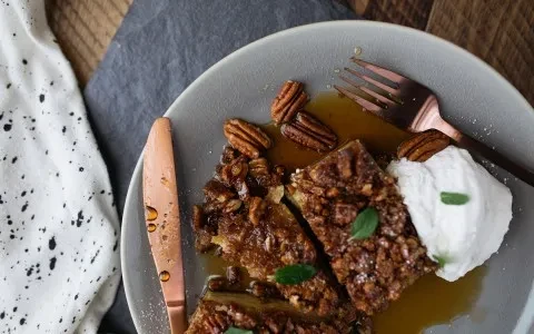 Pecan crumble dessert slices with syrup, whipped cream, and mint.