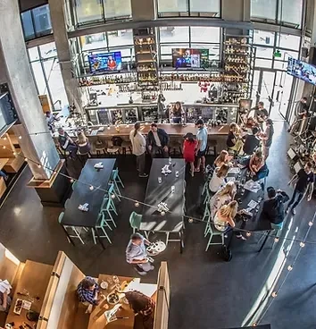 Multi-level, industrial-chic restaurant and bar bustling with many people.
