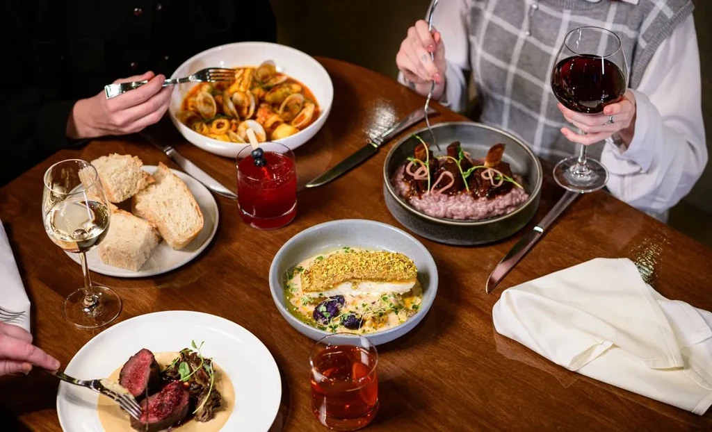 Overhead view of a dining table with gourmet food, drinks, and diners.