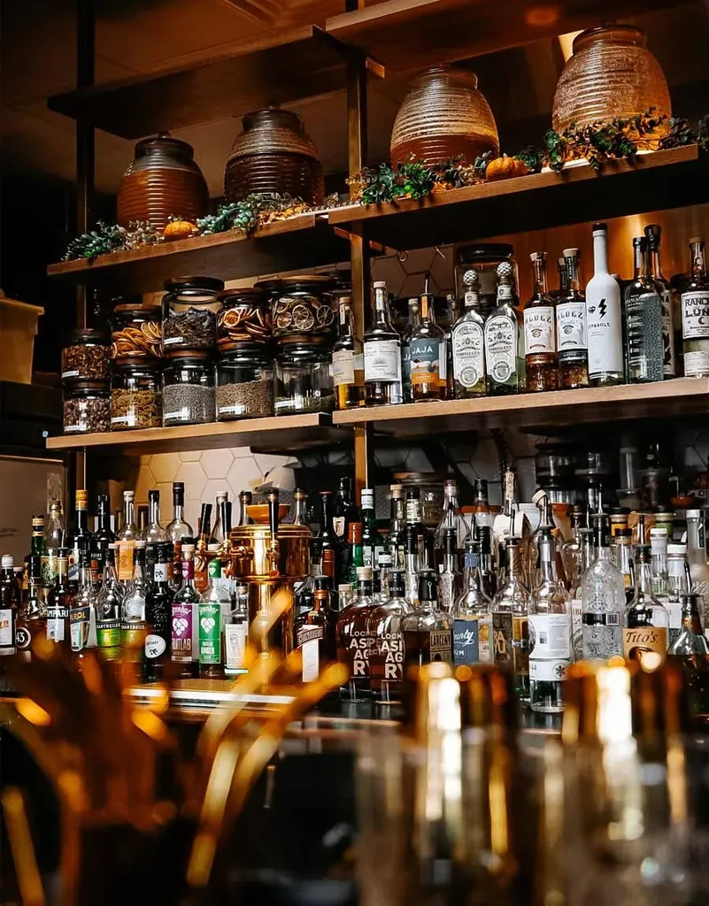 Well-stocked bar shelves with liquor bottles, cocktail ingredients, and autumnal decor.