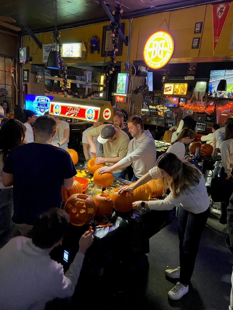 Group of people carving pumpkins at a bar Halloween event.