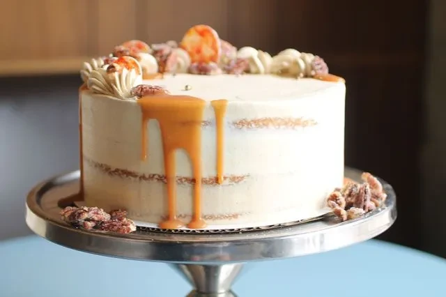 Semi-naked cake with caramel drips, pecans, and candied orange.