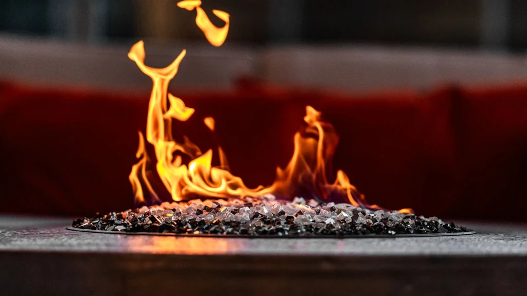 Close-up: Modern fire pit with vibrant flames over clear and dark fire glass.