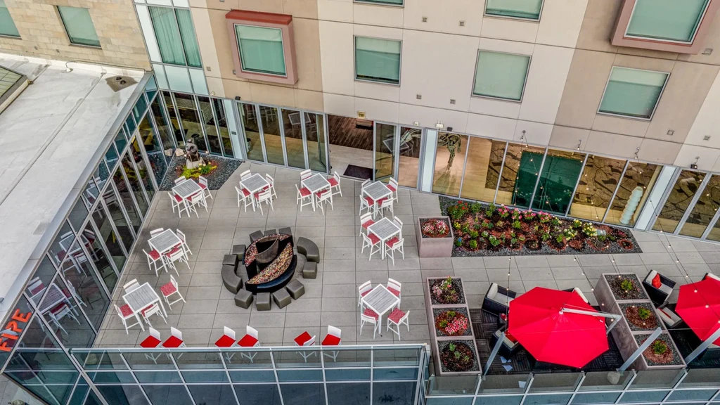 Modern rooftop patio with dining, lounge seating, fire pit, and umbrellas.
