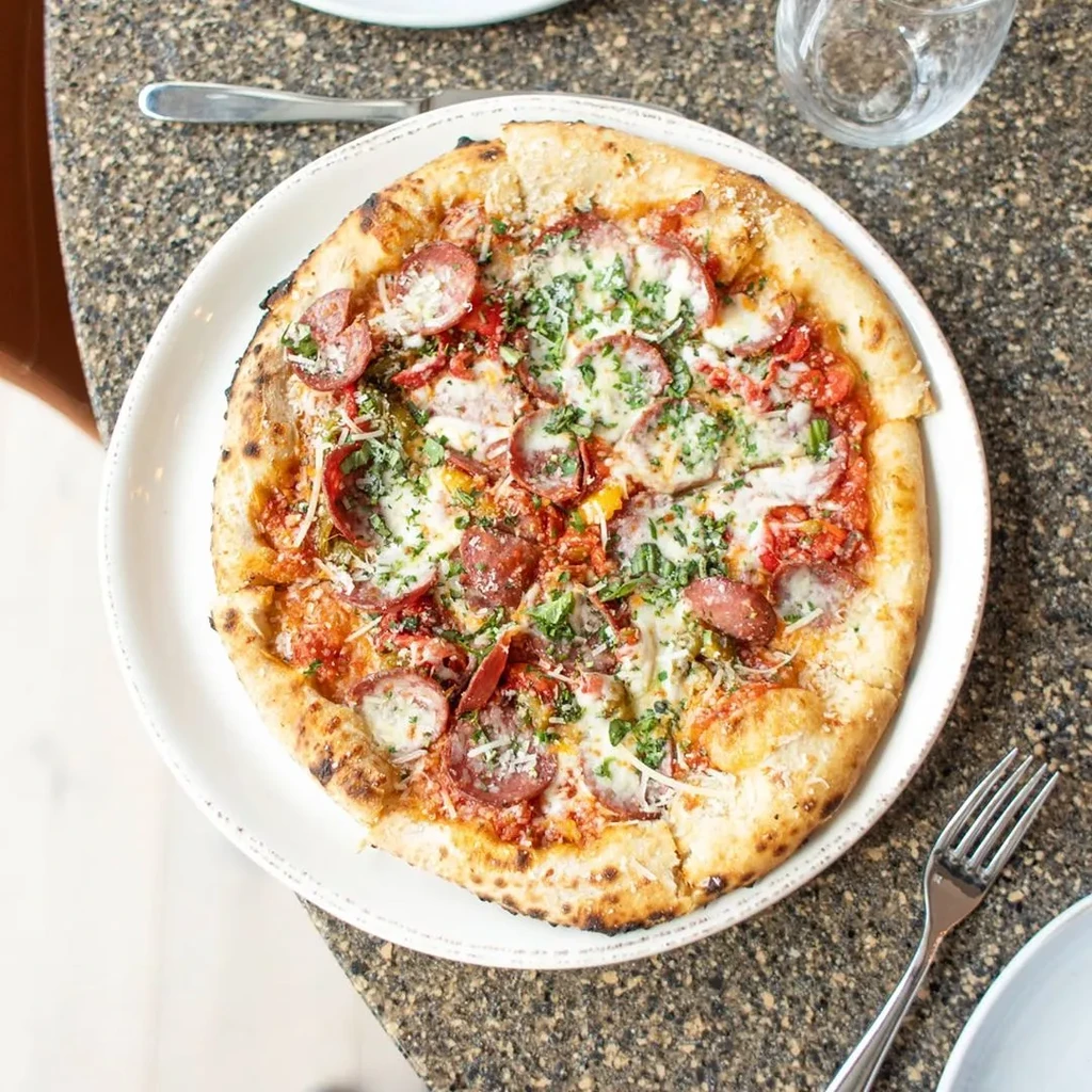 Overhead close-up of freshly baked pizza with pepperoni, cheese, herbs.