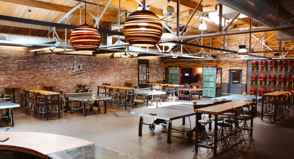 Industrial-chic bar interior with ping-pong tables, shipping containers, and a disco ball.