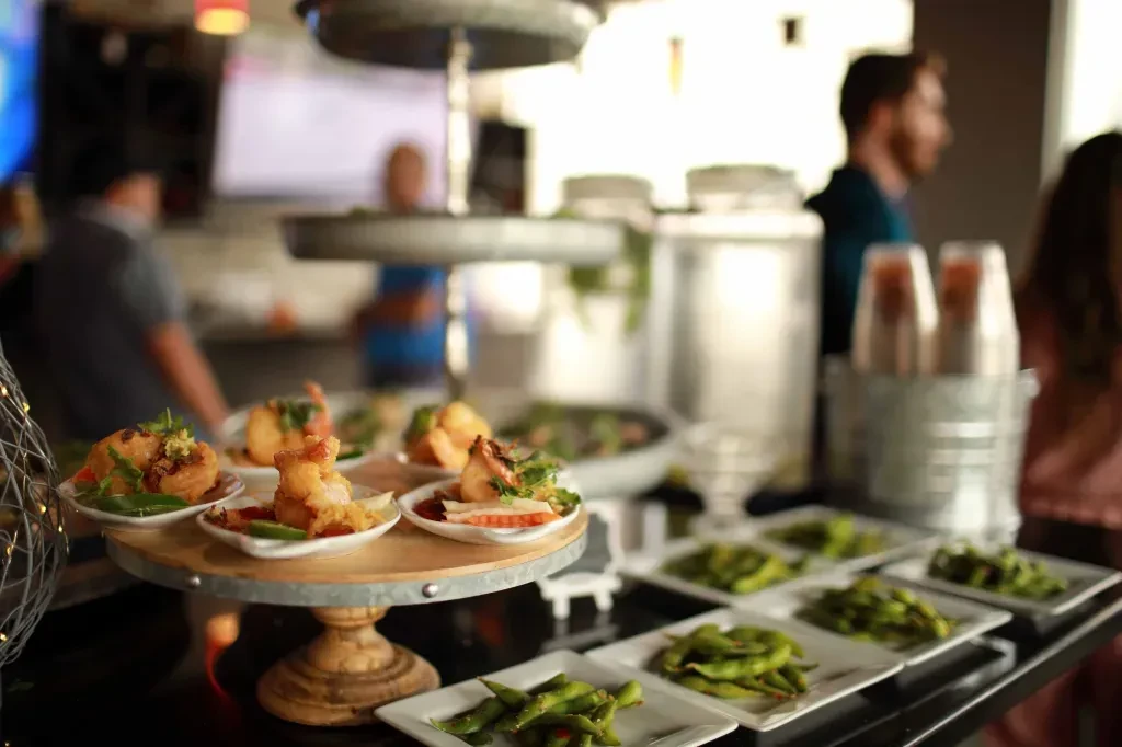 Buffet with a rustic tiered stand of appetizers and edamame plates.