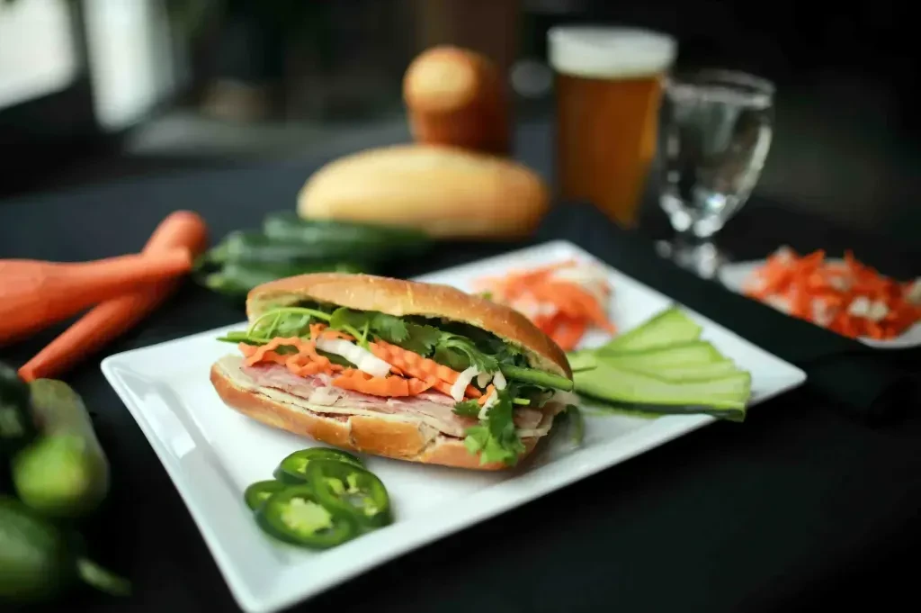 Vietnamese Banh Mi sandwich, sliced, revealing meats, pickled vegetables, and jalapeños.