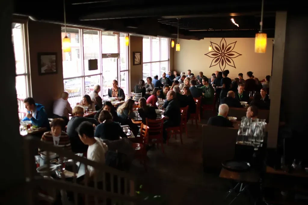 Bright, bustling restaurant interior with diners, staff, and modern decor.