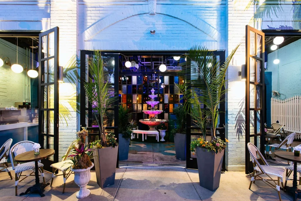 Restaurant exterior with outdoor seating and a pink-lit fountain.